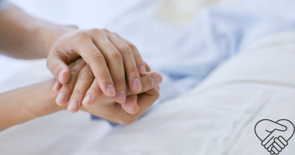 Close-up of a caregiver holding the hand of a person living with dementia to provide comfort and connection.