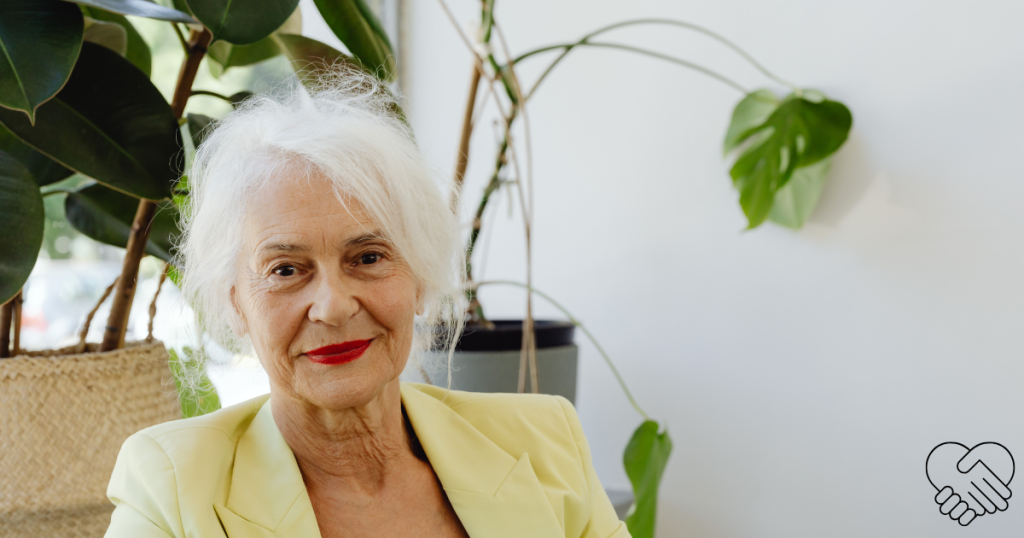 A smiling, silver-haired senior woman in a home setting, looking into the camera with a confident and balanced expression.