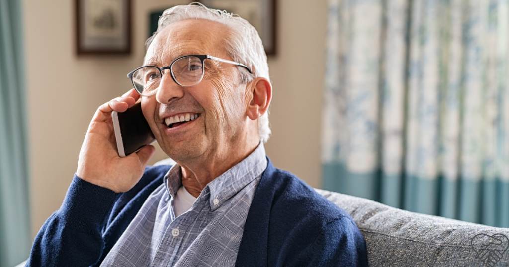 An elderly person smiling warmly while talking on the phone at home, illustrating how easy it is to stay connected with loved ones to support brain health.