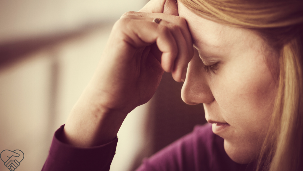 “I Am Not Patient Enough” – Guilt and Remorse A middle-aged woman sitting with her head lowered, showing signs of exhaustion and guilt while caring for a loved one with dementia at home.