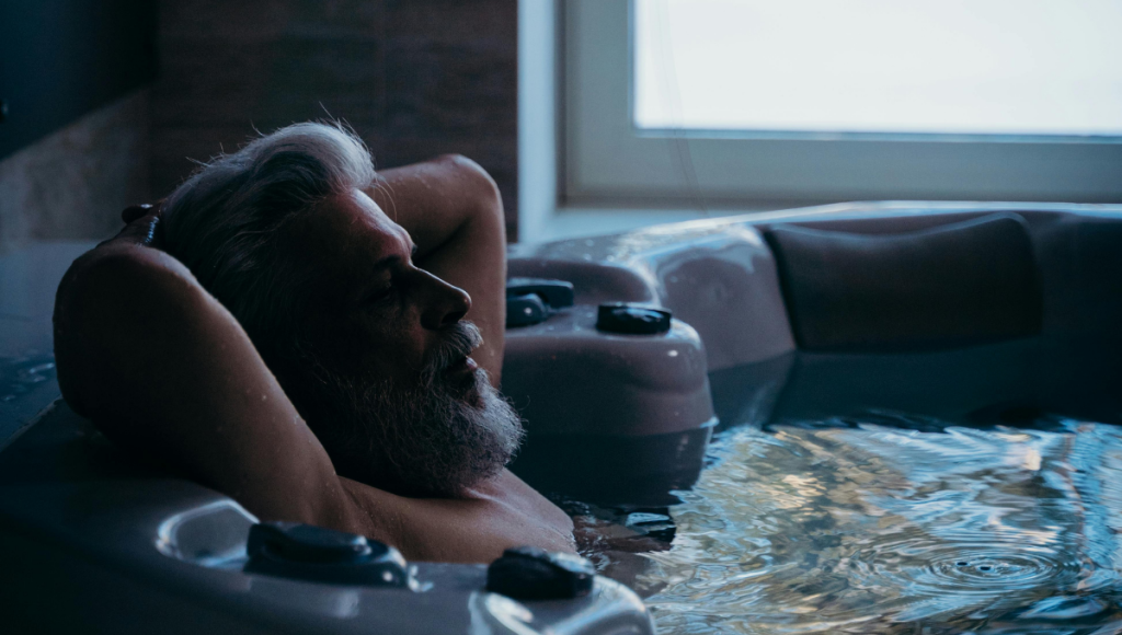 What to do if a person with dementia refuses to bathe? – Practical Solutions An elderly man sitting calmly in a bathtub while a caregiver offers a supportive hand. A safe and peaceful bathroom environment for home dementia care.